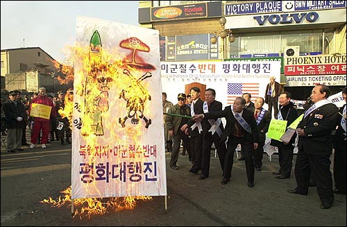 김정일 위원장과 핵무기 그림이 그려진 홍보판을 불태우고 있다. 